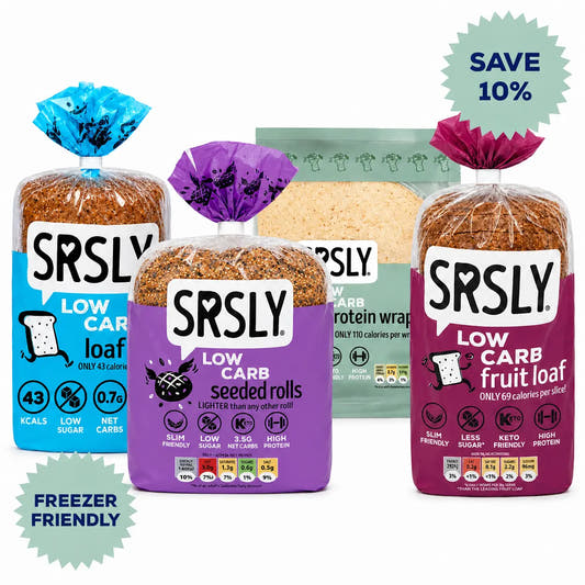 Four packaged SRSLY low-carb grocery items on a white background: a loaf of bread with a blue package, seeded rolls with a purple package, wraps with a green package and fruit loaf with a magenta package. A green 'SAVE 10%' badge appears top right, and a light blue 'FREEZER FRIENDLY' badge appears bottom left.