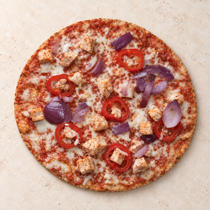 Uncooked SRSLY low carb spicy chicken pizza with a thin base, chicken, red onion and Roquito peppers
